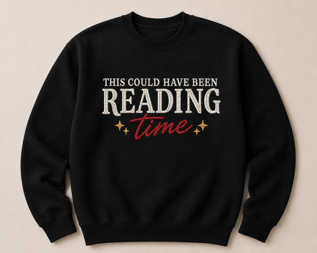 A black crewneck sweatshirt with a graphic text design reading 'THIS COULD HAVE BEEN READING time' in white and red, with small gold stars, displayed on a light beige background.