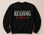 A black crewneck sweatshirt with a graphic text design reading 'THIS COULD HAVE BEEN READING time' in white and red, with small gold stars, displayed on a light beige background.