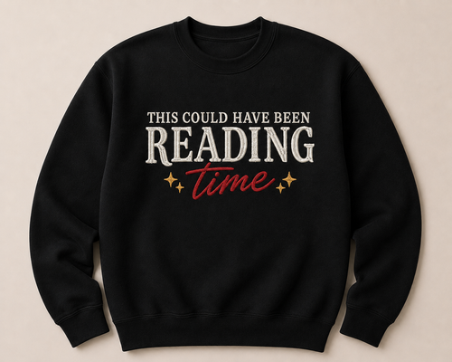 A black crewneck sweatshirt with a graphic text design reading 'THIS COULD HAVE BEEN READING time' in white and red, with small gold stars, displayed on a light beige background.